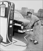 A man on skateboard pumping gas into a car.