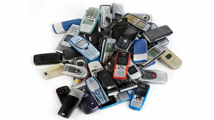 A pile of old cell phones sitting on top of each other.