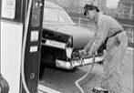 A man on skateboard pumping gas into a car.