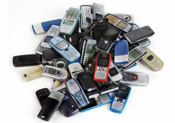 A pile of old cell phones sitting on top of each other.
